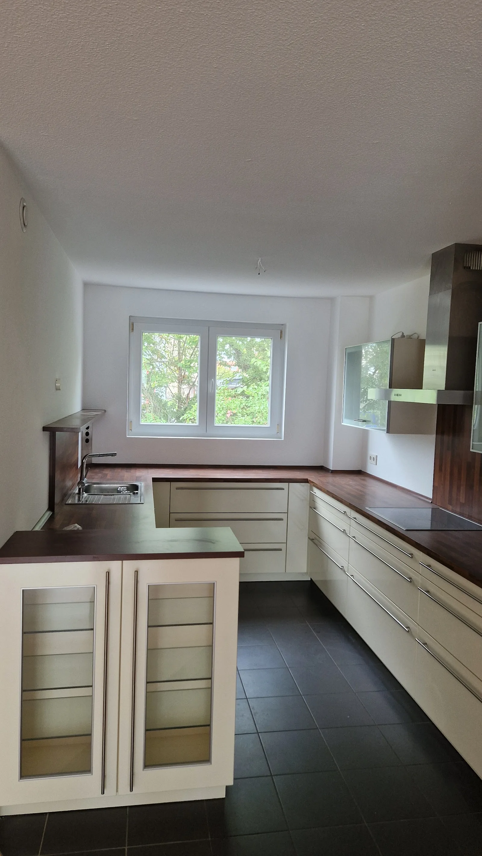 Fertige Küche mit cremefarbenen Fronten und dunklem Fliesenboden