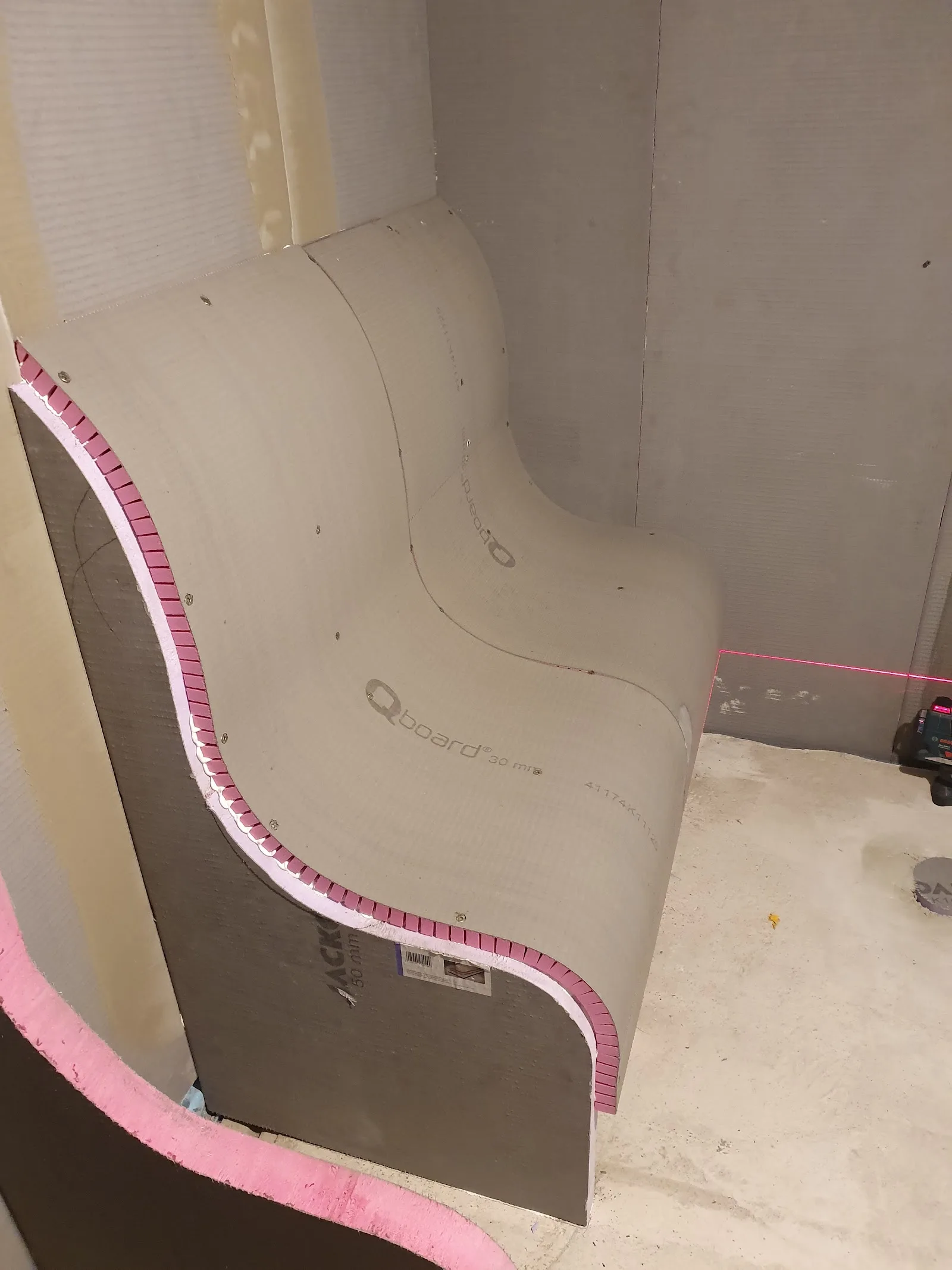 Gebogene Duschwand im Rohbau mit rosa Dichtband entlang der Rundung